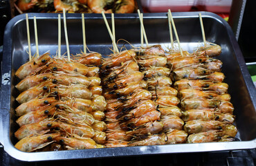 Unusual Thai street food — grilled shrimp heads on skewers, served in a metal tray, capturing the bold flavors and adventurous spirit of local cuisine.