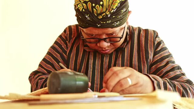 Javanese craftsman carving a wayang kulit shadow puppet