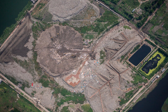 Aerial view of a vast landfill with piles of waste, dark patches, and rectangular pools, creating a stark contrast between decay and containment, Dhaka, Dhaka Division, Bangladesh.
