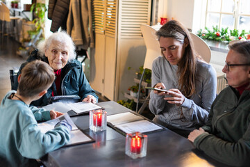 Family reading menus in restaurant with candles and smartphone