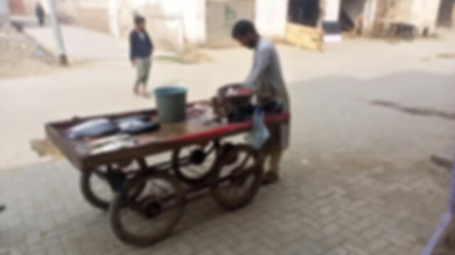 Street Vendor Cutting Fish on a Cart in a Blurred South Asian Town Square