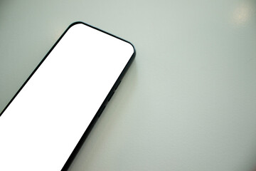 A smartphone is placed on a minimalist white table, copy space.