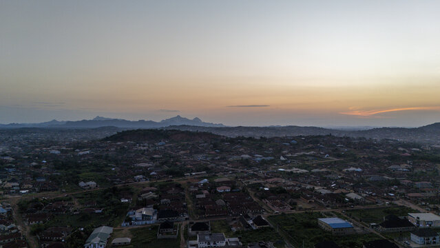 Aerial view of the sprawling city nestled amidst rolling hills, where rooftops meet the horizon under the soft glow of the setting sun, Akure, Ondo, Nigeria.