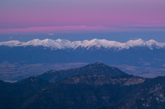 Aerial view of snow-capped peaks kissed by the soft hues of dawn, a dance of light and shadow over majestic mountains, Derese, Zilina Region, Slovakia.