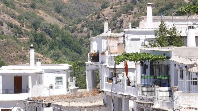 Traditional white houses of Pampaneira, in the Alpujarra region of Granada, Andalusia. Detail of tall chimneys and flat roofs with the Poqueira Gorge in the background.