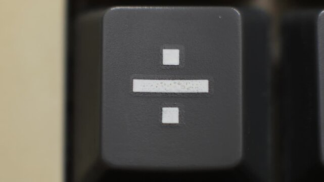 Macro close up of a division key being pressed for budgeting and fair splits