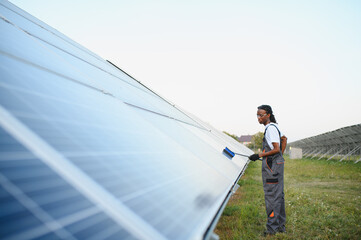 Naklejka premium African american man cleaning solar panel field