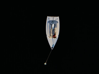 Aerial view of a small white sailboat cuts through the dark expanse of water, its angular form a stark contrast against the inky depths, Boston, Massachusetts, United States.