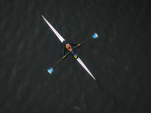 Aerial view of a lone rower gliding across the dark waters, a study in stark contrasts and focused determination, Boston, Massachusetts, United States.