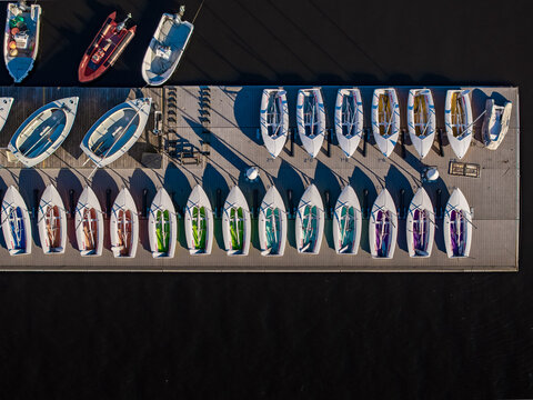 Aerial view of colorful sailboats lined up neatly in a row along a dock, contrasting vividly with the dark water, Boston, Massachusetts, United States.