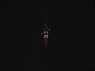 Aerial view of a solitary canoe slicing through the dark waters, a tiny vessel carrying figures in the vast expanse, Boston, Massachusetts, United States.