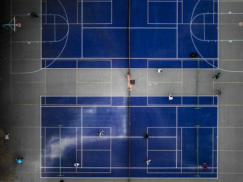 Aerial view of vibrant blue and gray courts create a striking geometric pattern, framed by figures in motion, a testament to urban recreation, Boston, Massachusetts, United States.