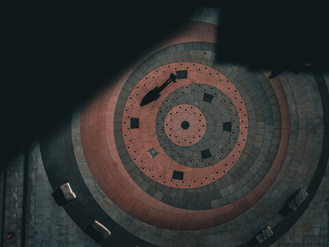 Aerial view of a circular brick pattern with concentric rings and a dark silhouette, a stark contrast of light and shadow creating a dramatic effect, Boston, Massachusetts, United States.