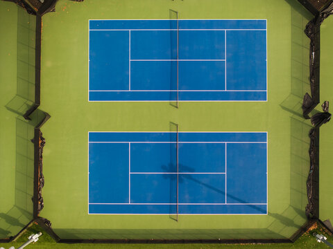 Aerial view of stark blue tennis courts contrasting with the lush green surroundings, creating a vibrant geometric pattern from above, Boston, Massachusetts, United States.