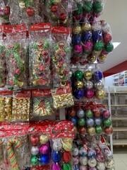 Colorful decorative ornaments knick knacks for birthday celebrations or religious celebration decorations sold in shops. The items include shiny, spherical red, green, gold, pink, and silver.