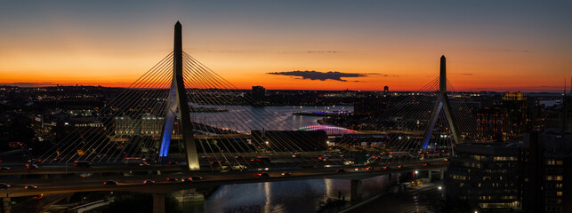 Aerial view of the Zakim Bridge glows as cars stream across the bridge against the fiery sunset sky, Boston, Massachusetts, United States.