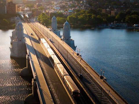 Aerial view of a train gliding across the Longfellow Bridge, spanning the Charles River under the warm glow of the sun, Boston, Massachusetts, United States.
