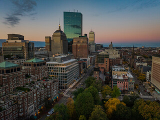 Aerial view of Boston's skyline glows with the Prudential Tower and John Hancock Building piercing the twilight, as autumn hues paint the Common, Boston, Massachusetts, United States.