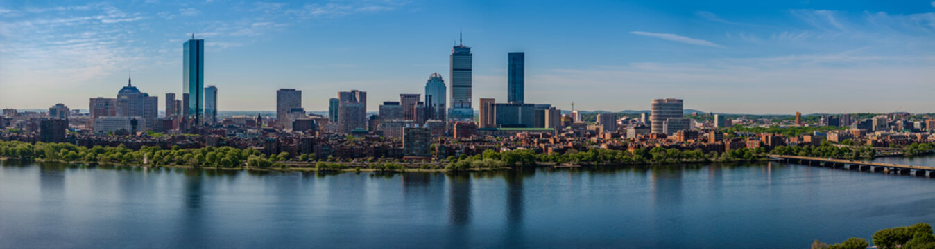 Aerial view of Boston's skyline rises majestically above the Charles River, with the Hancock and Prudential towers gleaming under a clear sky, Boston, Massachusetts, United States.