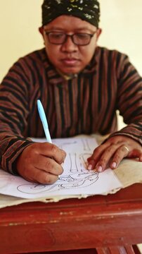 Javanese man drawing a traditional wayang puppet