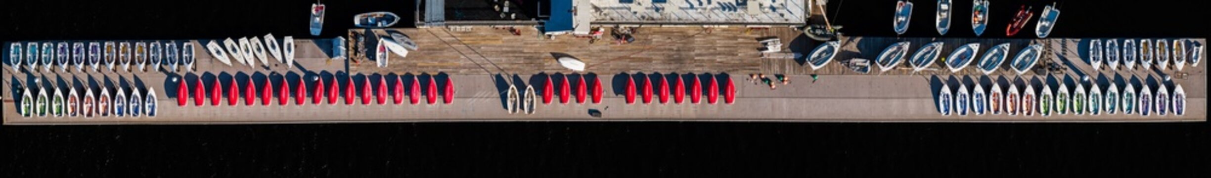 Aerial view of a neat array of colorful boats lined up on a pier, stark against the dark water, Boston, Massachusetts, United States.