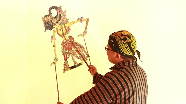 Indonesian puppeteer performing with a wayang kulit shadow puppet