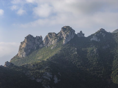 Aerial view of rugged mountain peaks crowned with jagged rock formations, draped in shadows and sunlight, Erchie, Amalfi Coast, Italy.