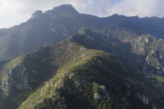 Aerial view of rugged, verdant mountains rise sharply, their slopes textured with trees, under a soft, diffused light, Erchie, Amalfi Coast, Campania, Italy.