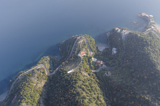 Aerial view of serpentine roads carve through verdant hills, meeting the azure sea in a stunning coastal dance, Erchie, Amalfi Coast, Campania, Italy.
