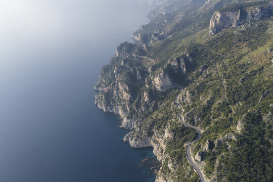 Aerial view of the Amalfi Coast's dramatic cliffs meet the serene sea, with winding roads carving through the lush, steep terrain, Erchie, Amalfi Coast, Campania, Italy.