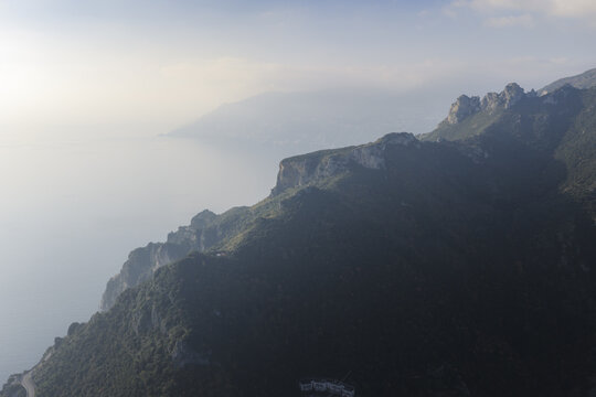 Aerial view of rugged cliffs plunging into the turquoise sea, a dramatic meeting of land and water, Erchie, Amalfi Coast, Campania, Italy.