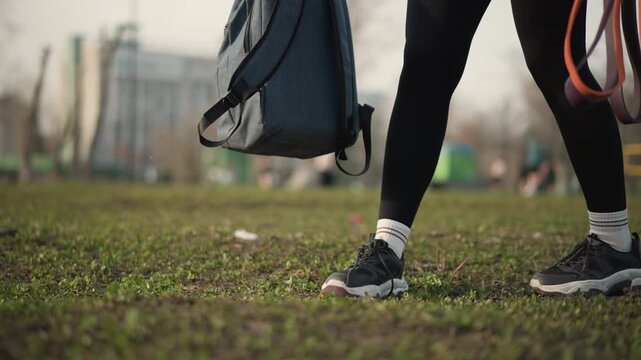 Closeup Of Walking, Photograph Captures Rhythmic Walking With Backpacks Nearby And Trailing Leashes, Detailed Candid Shot Of Feet In Sneakers Crossing Textured Grass With Backpack And Trailing Leash