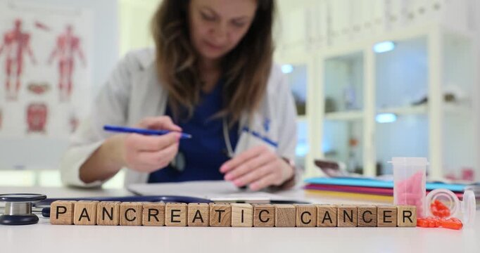 Wooden blocks on desk spell phrase Pancreatic Cancer by medical files and medicine. Woman doctor writes detailed notes evaluating pancreas tumor risk