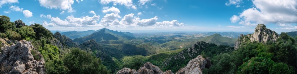 Obraz premium Scenic panorama of verdant mountain landscape with clear blue sky and fluffy clouds