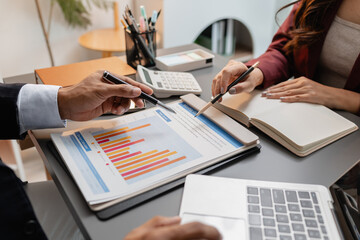A collaborative startup meeting showing professionals reviewing financial charts and discussing strategic ideas in a modern office setting.