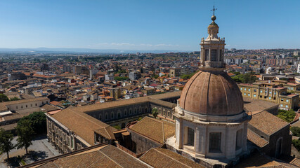Obraz premium Aerial closeup of the dome of the church of San Nicolò l'Arena, a Roman Catholic church, in the city of Catania, Sicily, southern Italy. In the background there is the Sicilian town. Sunny day morning