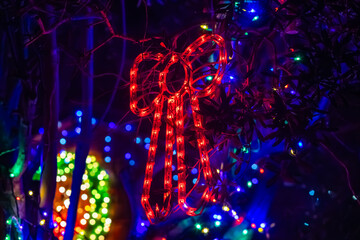 Christmas decoration made of lights in the shape of a red bow, closeup
