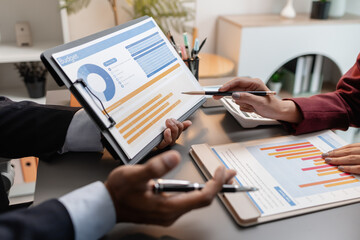 A collaborative startup meeting showing professionals reviewing financial charts and discussing strategic ideas in a modern office setting.