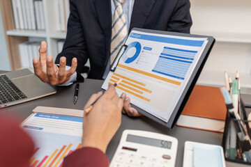 A collaborative startup meeting showing professionals reviewing financial charts and discussing strategic ideas in a modern office setting.