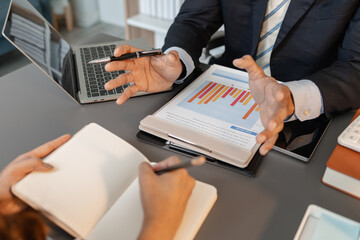 A collaborative startup meeting showing professionals reviewing financial charts and discussing strategic ideas in a modern office setting.