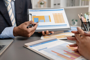 A collaborative startup meeting showing professionals reviewing financial charts and discussing strategic ideas in a modern office setting.