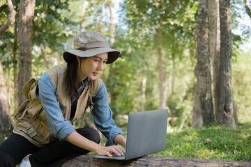 Female botanist examines plant leaves and grass in outdoor field for agricultural eco