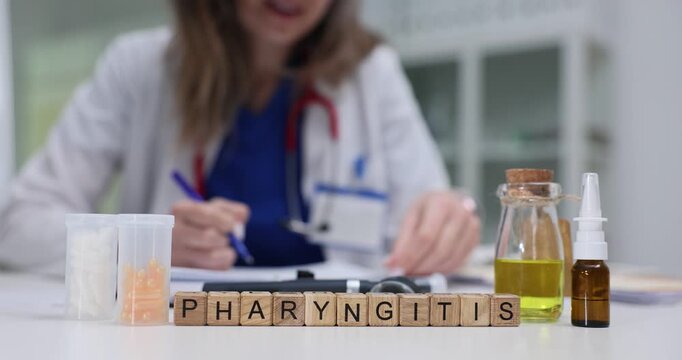 Wooden blocks spell word Pharyngitis near spray bottle and yellow liquid. Woman doctor checks throat chart writing plan for patient sore throat care