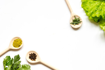 various spices in wooden spoons on white background top view