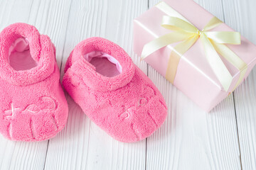 baby's bootees and gift box on wooden background