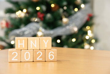 Craft wooden cube blocks HNY 2026 with Christmas tree defocused background. Texts and numbers on wooden blocks with copy space. 2026 happy new year idea concept.