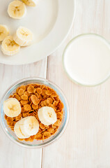 flakes in bowl with banana on wooden background top view