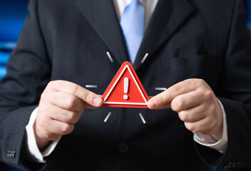 A businessman and a danger warning sign. An official and an urgent message about a problem. Risk...