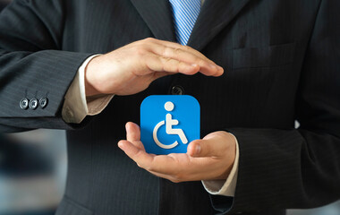 A businessman holds a symbol for people with disabilities. Support for people with limited mobility. A bar-free environment in the city. Inclusion policies improve accessibility