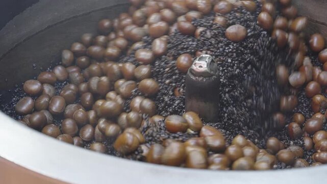 Vendor stirring chestnuts (Kao Luck) in heated black coffee beans or sand to roast them evenly. Yaowarat Road, Bangkok.